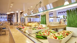 Un bufé con diversas opciones de comida, incluyendo ensaladas y aperitivos, en un ambiente interior bien iluminado.
