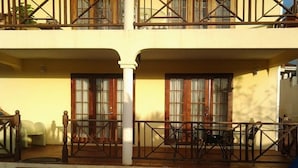 A hotel with a pool area, outdoor seating, and a balcony with wooden railings. - Sungold House Barbados (Speightstown)