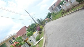 A residential street with houses, a clear sky, and a sidewalk.