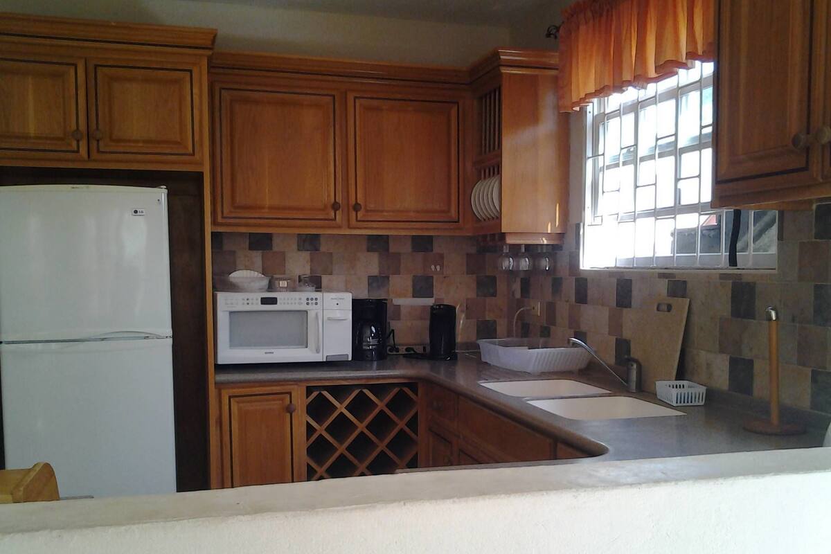 A kitchen with wooden cabinets, a white refrigerator, a microwave, a coffee maker, and a sink.
