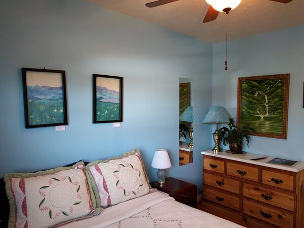 Un dormitorio con cama, cómoda y dos cuadros en la pared.