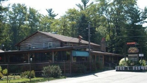 A rustic building with a sloped roof, a covered porch, and a sign indicating a restaurant. - Fern Ridge Motel (Blakeslee)