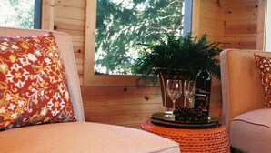 Una habitación acogedora con un sofá mullido, una mesita de noche tejida y una ventana con vistas a árboles.
