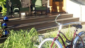 Un porche con dos sillas, una bicicleta y un tablón de anuncios en una pared de ladrillo.