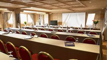 Une salle de conférence dotée de longues tables et de chaises rouges, ainsi que de plaques nominatives et de bouteilles d’eau.
