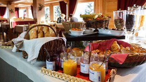 Una mesa de buffet con diversos productos para el desayuno, como pan, frutas y mermeladas.