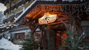 Un hotel con fachada de madera, un letrero que dice "Hotel de Savole" y un paisaje cubierto de nieve.