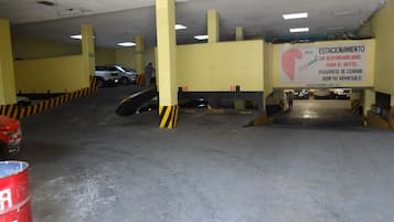Un aparcamiento de varios niveles con pilares amarillos y barreras señalizadas.