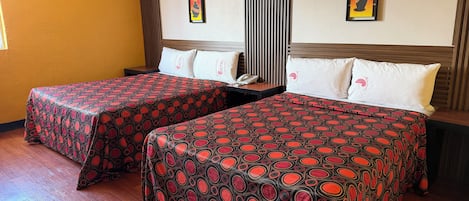 Une chambre d’hôtel avec deux lits, un plancher en bois, une fenêtre avec des stores et des œuvres d’art accrochées aux murs.