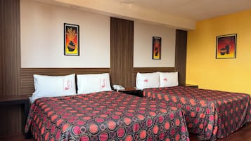 Habitación de hotel con dos camas, cada una con una colcha estampada, un cabecero de madera y una mesita de noche con un teléfono.