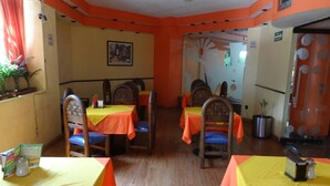Un comedor con mesas y sillas, un techo con una lámpara, y una pared con un cuadro enmarcado.