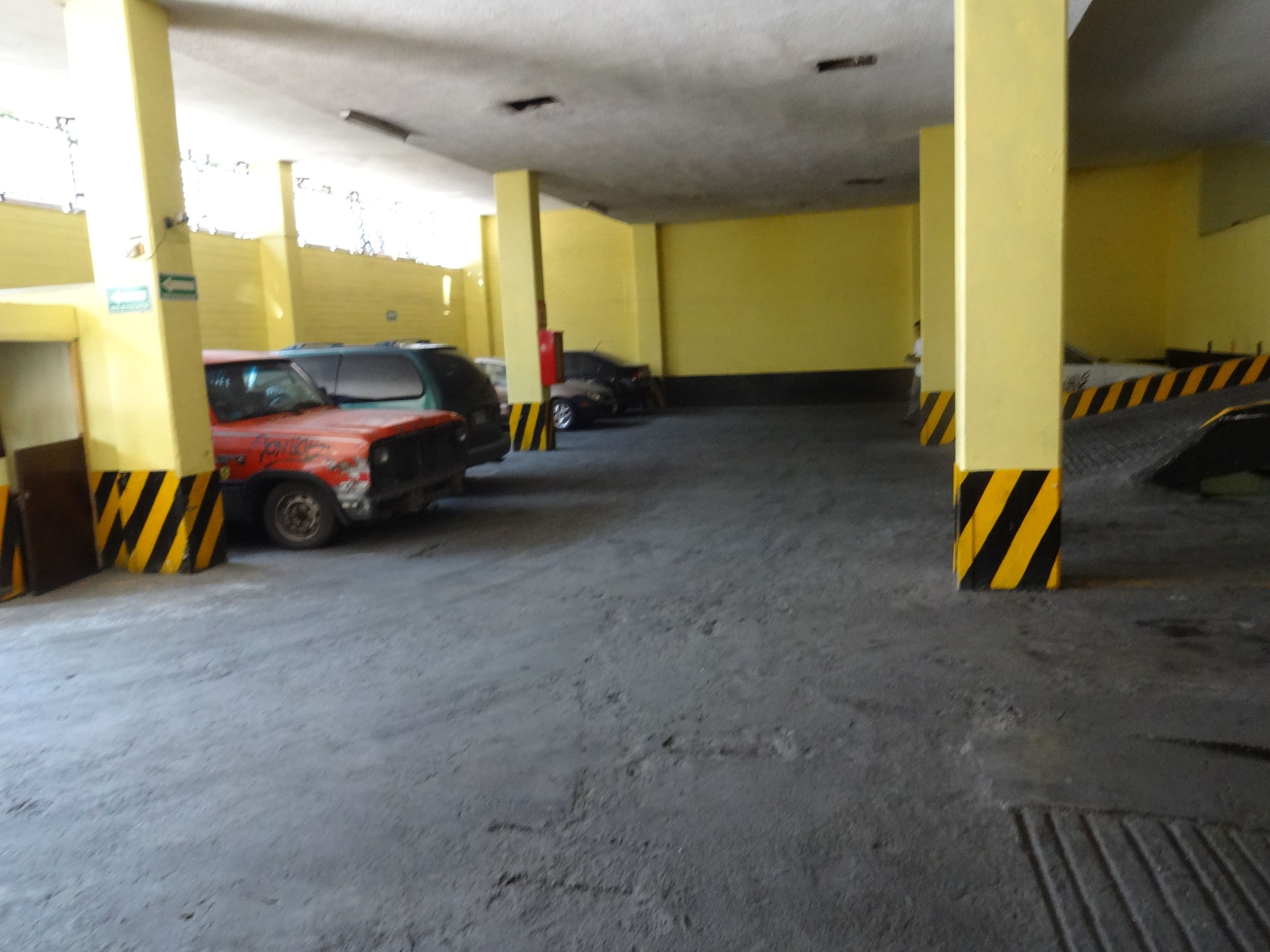A parking garage with yellow pillars and black and yellow striped barriers.