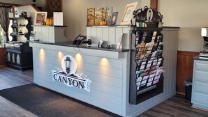 A reception desk with a 'CANYON' sign, a coffee machine, and a magazine rack. - The Canyon Motel (Wellsboro)