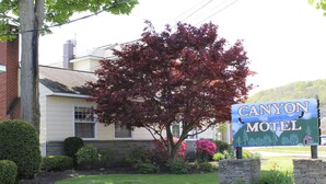 A motel sign with a tree and landscaping. - The Canyon Motel (Wellsboro)
