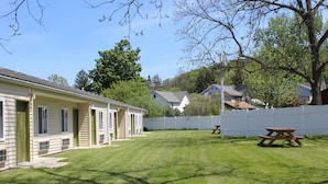A residential area with a well-maintained lawn, a picnic table, and a white fence. - The Canyon Motel (Wellsboro)