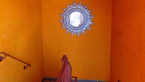 A narrow hallway with orange walls and a decorative mirror on the wall. - Central Inn Motel (Los Angeles)