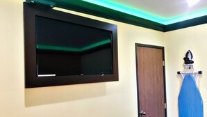 A room with a mounted television, a wooden door, and a blue ironing board. - Central Inn Motel (Los Angeles)