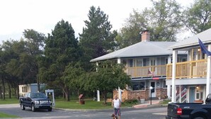 A residential street with a grassy area, a small tree, and a building with a balcony. - River Country Motor Lodge (Grayling)