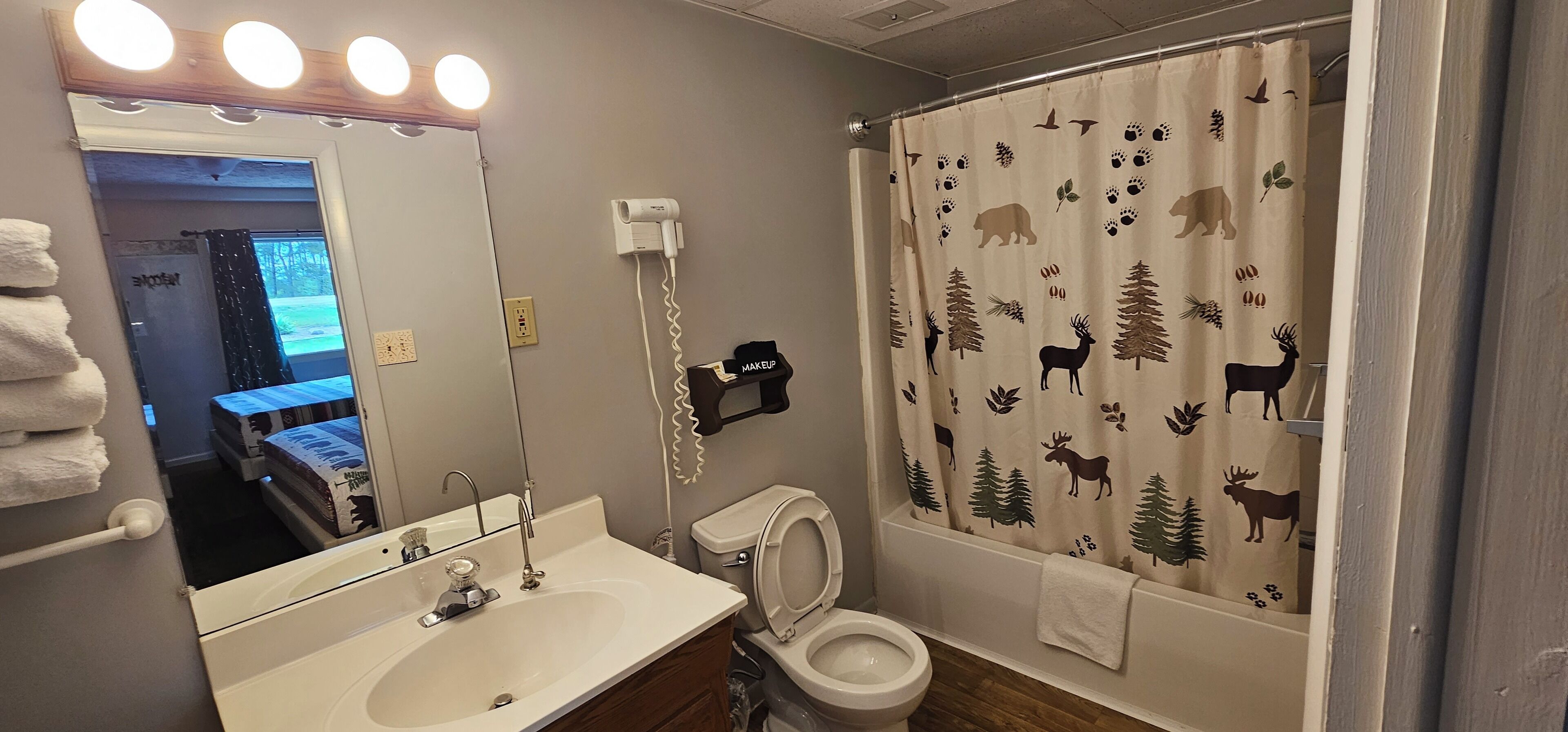 A bathroom with a sink, mirror, toilet, and a shower curtain with animal prints.