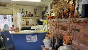 A reception area with a blue counter, a welcome mat, and autumn-themed decorations. - River Country Motor Lodge (Grayling)