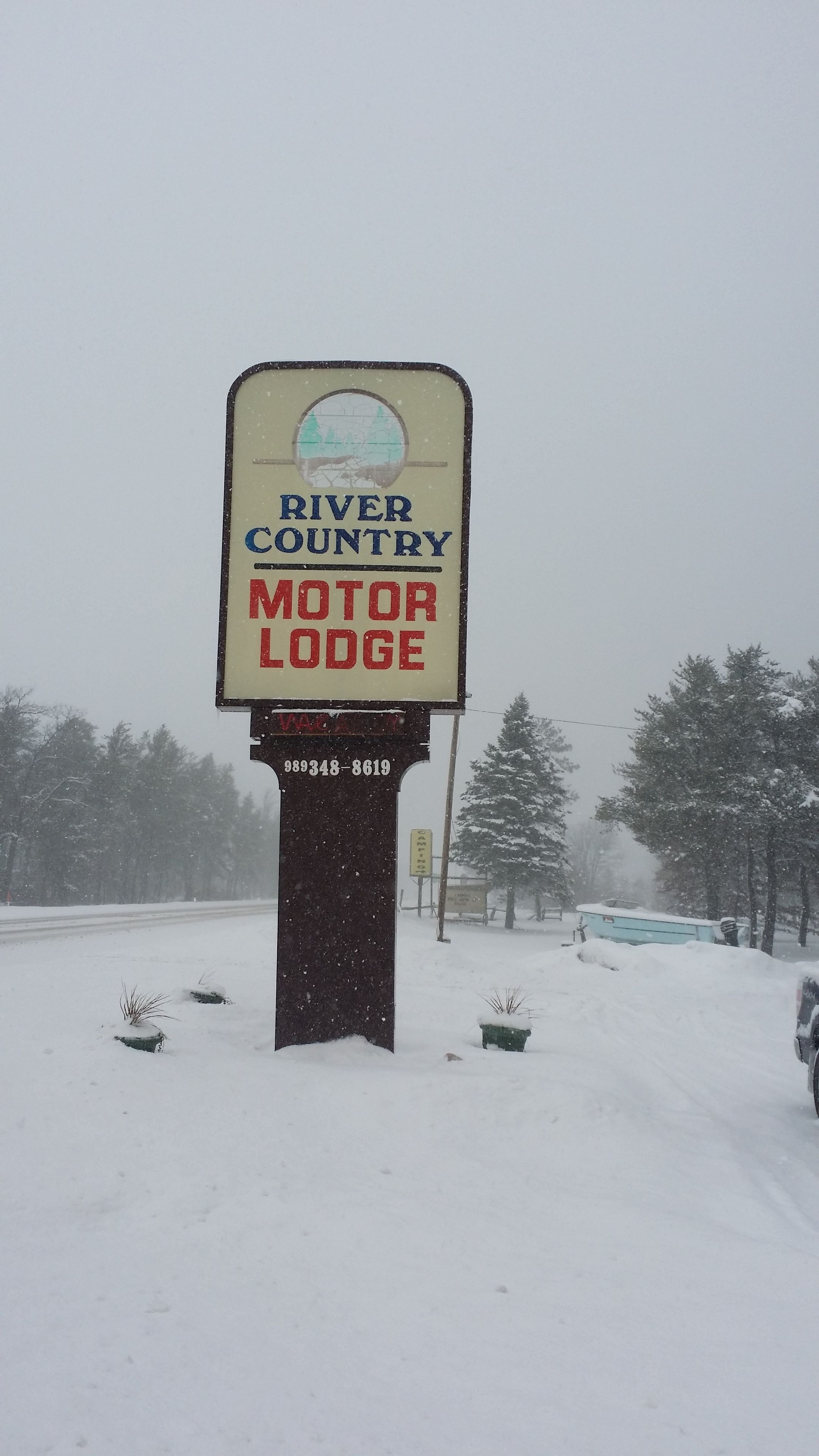 A sign for the River Country Motor Lodge with a phone number.
