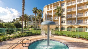 A hotel with a swimming pool, palm trees, and a fountain. - WorldMark Orlando - Kingstown Reef (Orlando)