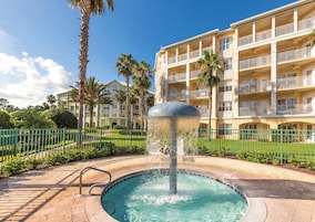 Ein Hotel mit Schwimmbad, Palmen und einer Springbrunnen.