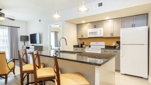 A modern kitchen with a central island, white cabinets, and stainless steel appliances. - WorldMark Orlando - Kingstown Reef (Orlando)