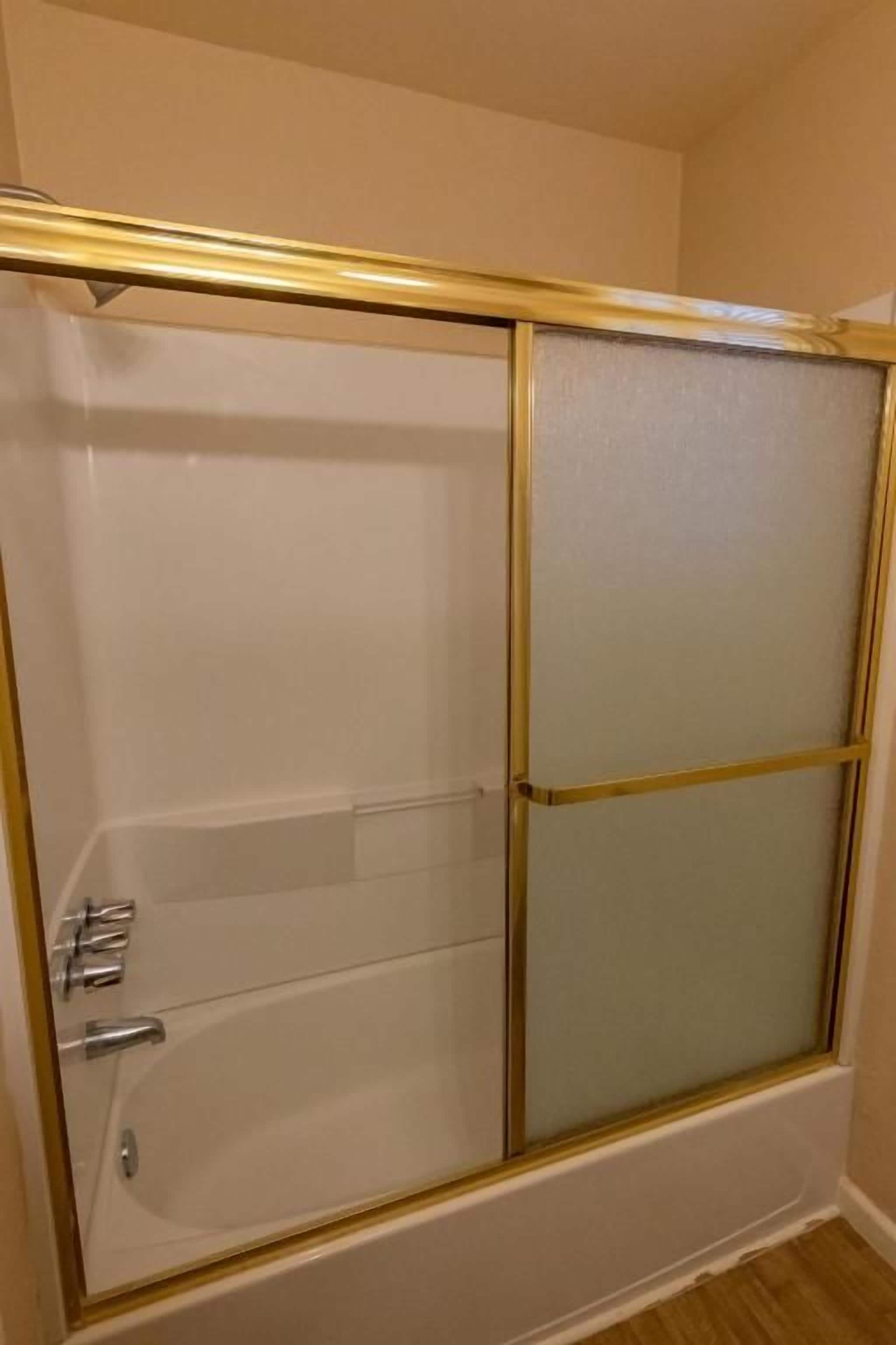 Een douchecabine met een glazen deur en een gouden rand.