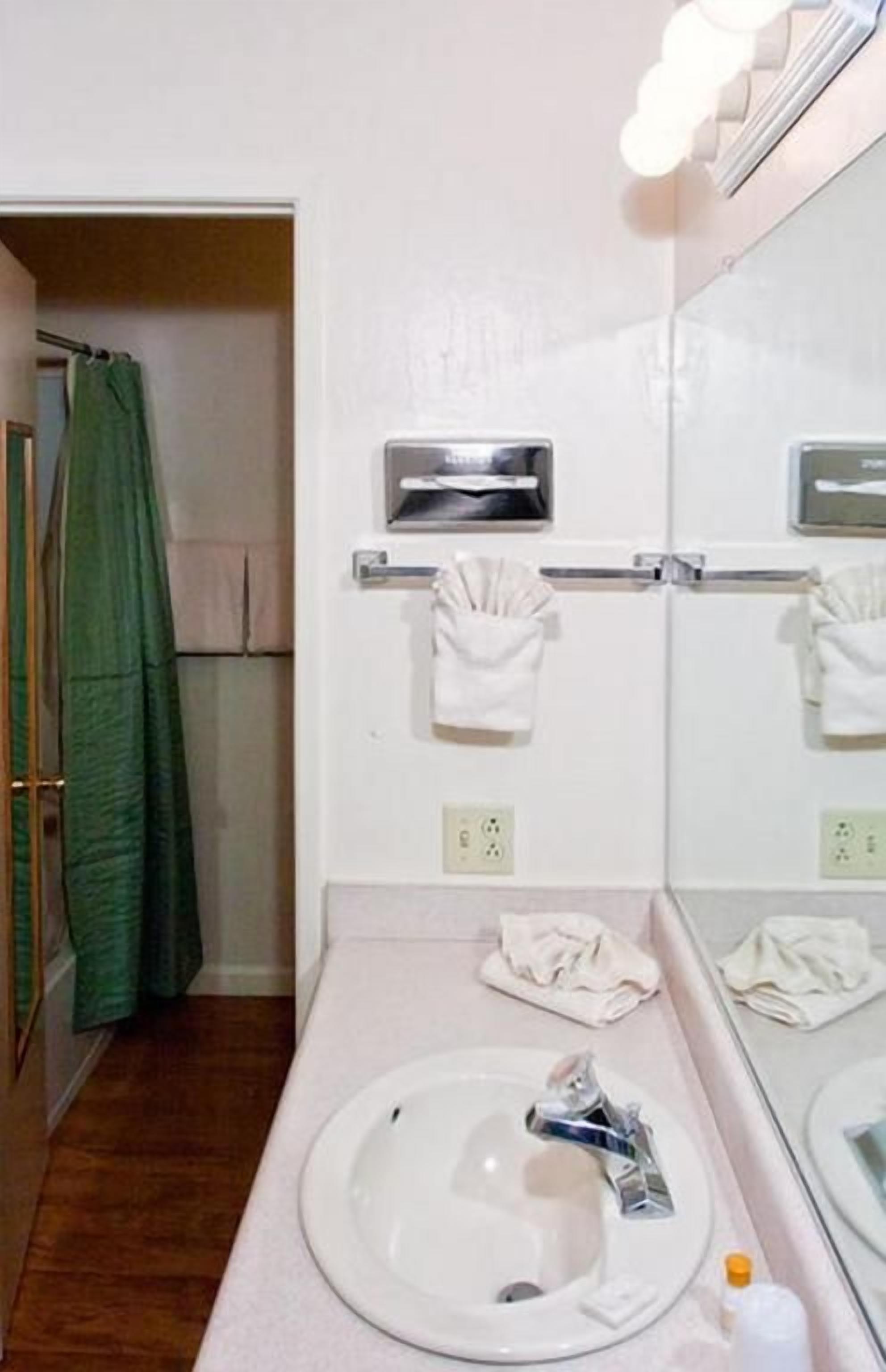 Ein Badezimmer mit Waschbecken, Handtuchspender und Spiegel.