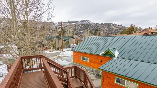 A wooden deck leading to a cabin with a green roof, surrounded by snow-covered ground and a mountainous backdrop. - June Lake Motel (June Lake)