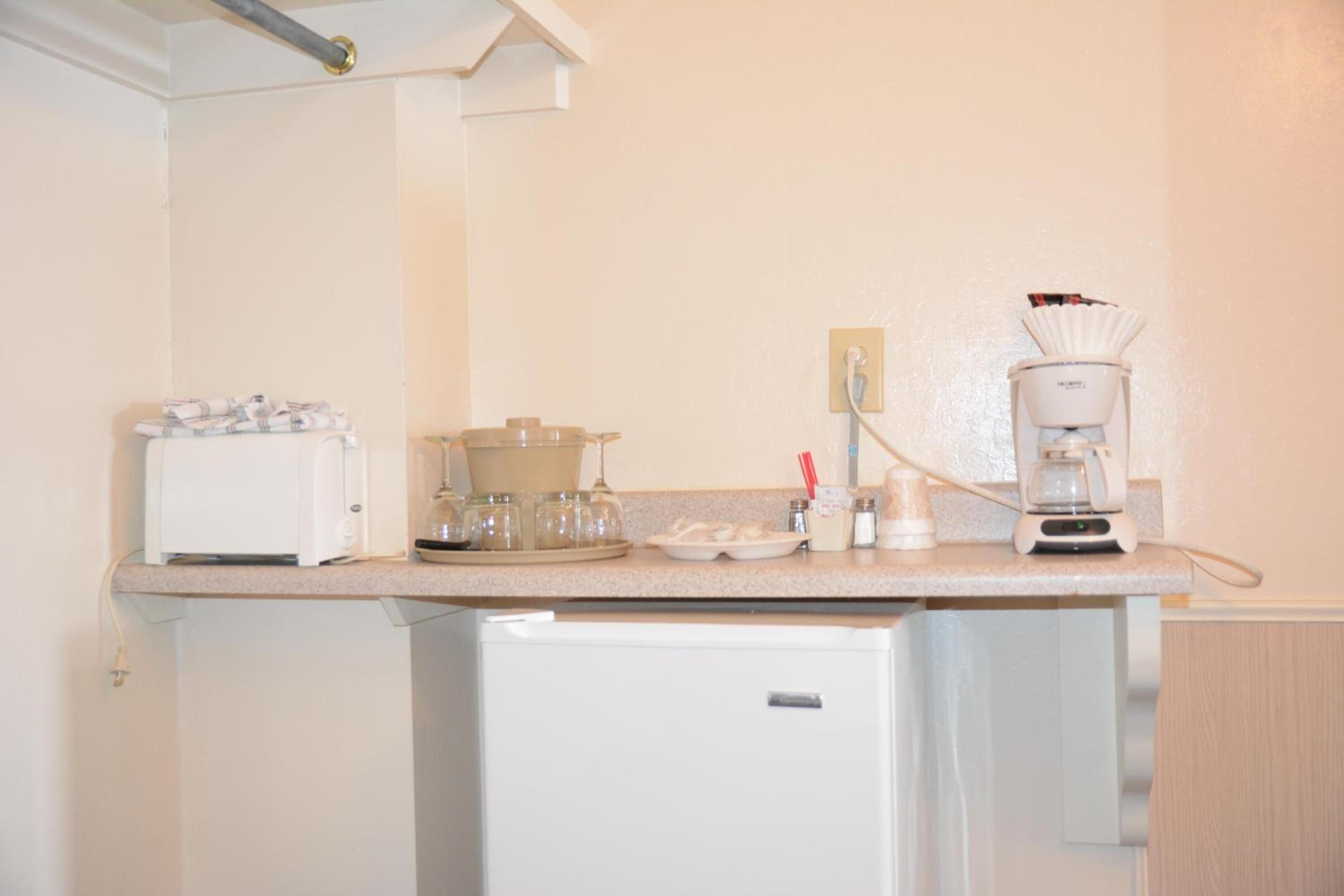 A compact kitchenette with a toaster, a coffee maker, and a small refrigerator.