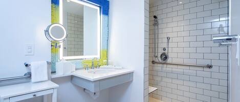 Un baño moderno con lavamanos, espejo y ducha blancos.