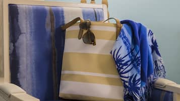 Una silla con un cojín a rayas y una manta azul, una lámpara y una cortina.