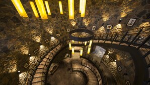 Un escalier en colimaçon avec des murs en pierre et des luminaires suspendus.
