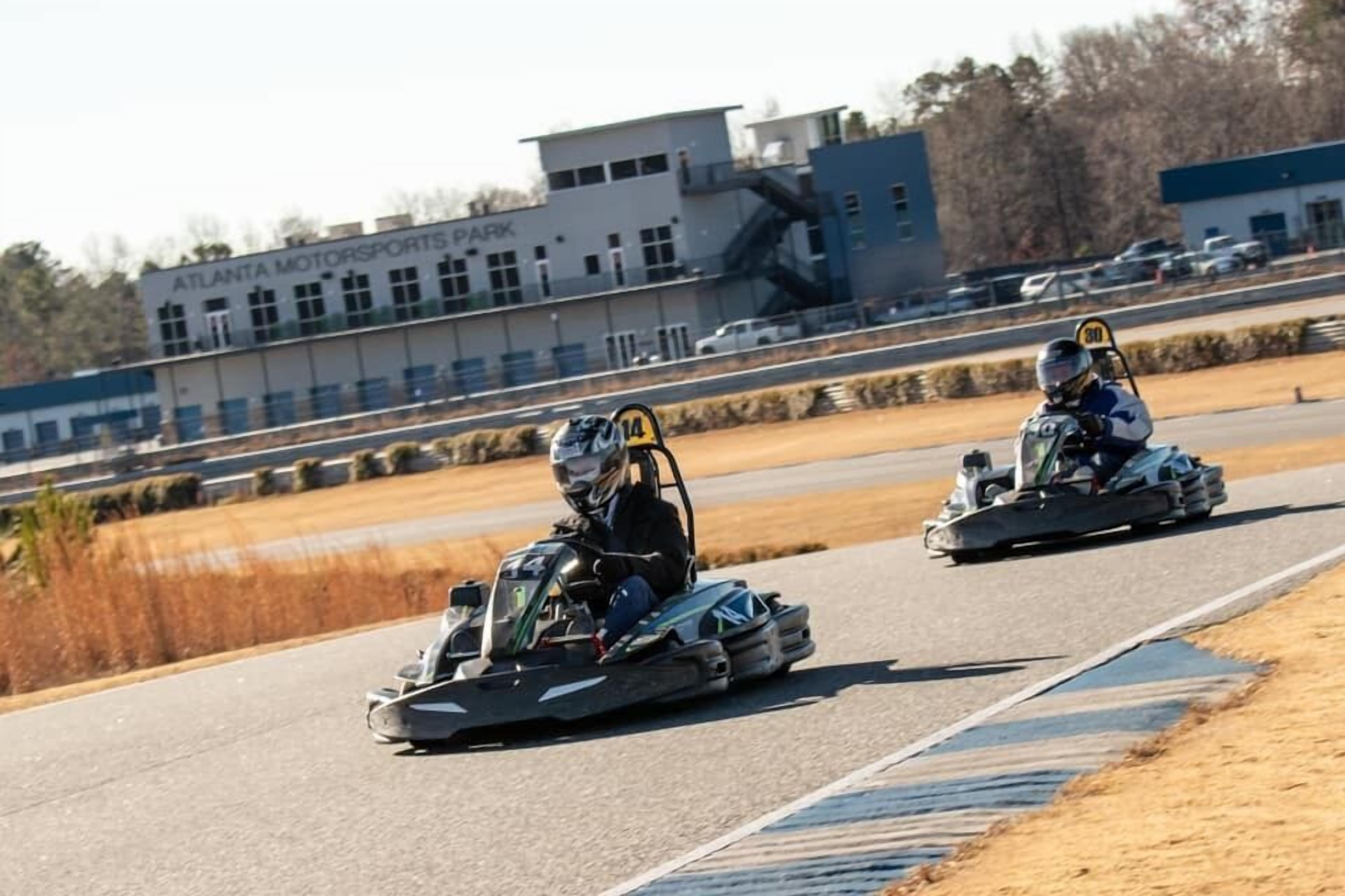 Two go-karts on a track with a building labeled "ATLANTA MOTORSPORTS PARK" in the background.