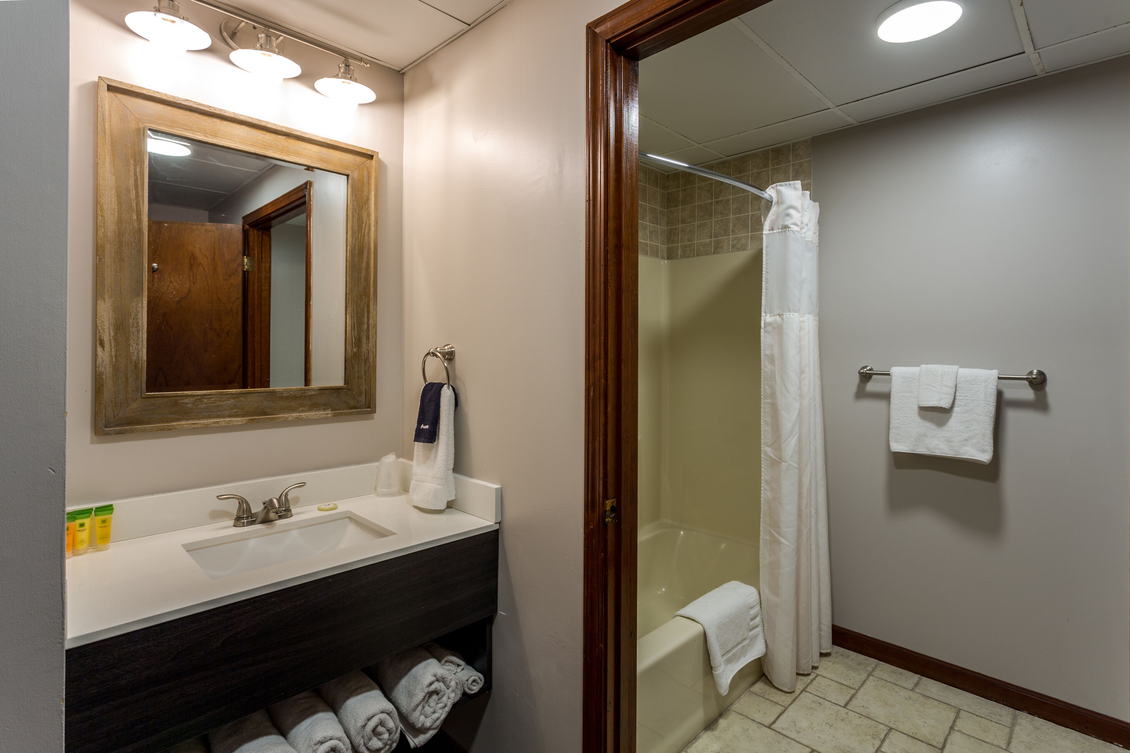 A bathroom with a sink, mirror, and shower.