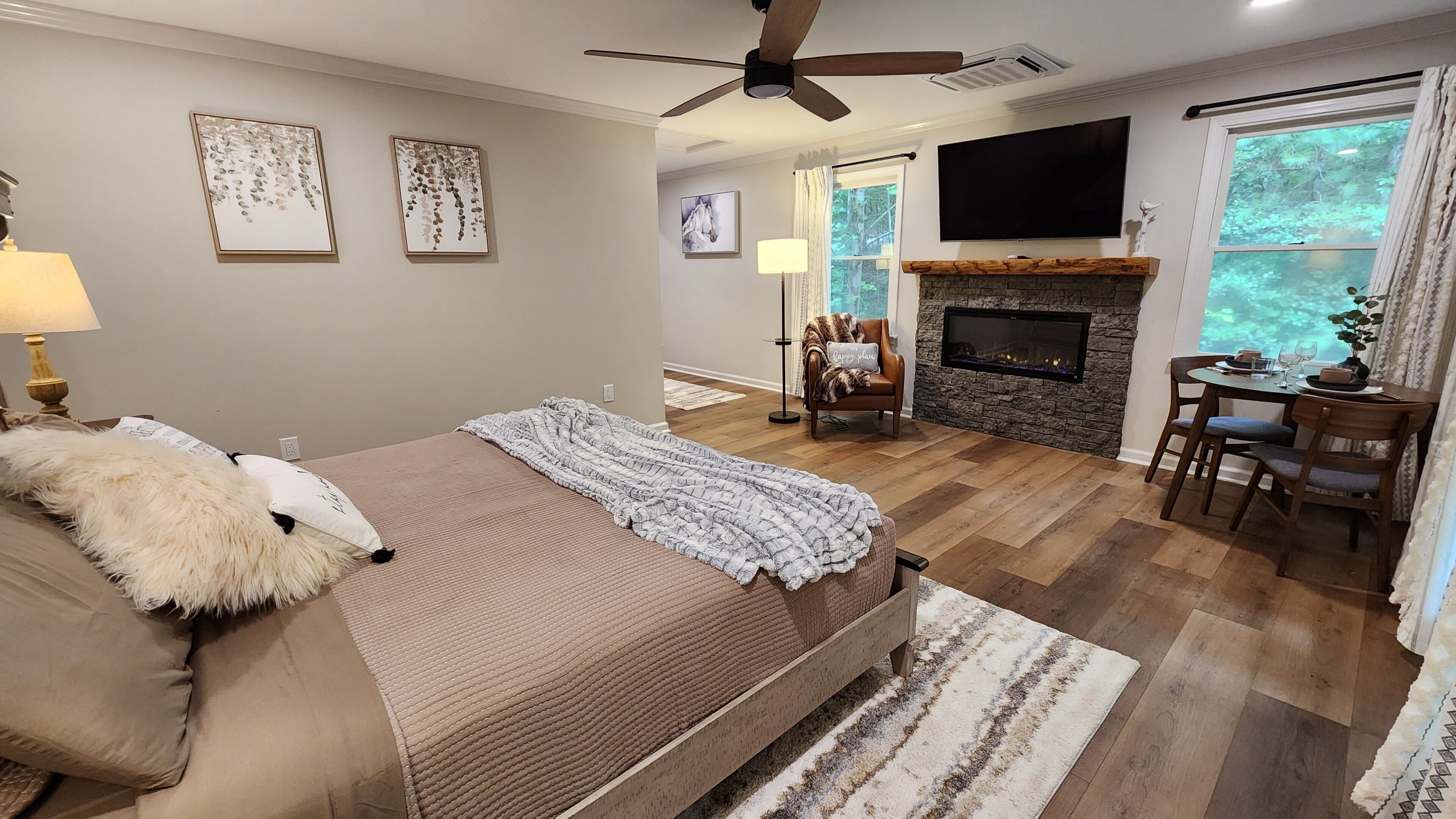 A bedroom with a large bed, a fireplace, a TV, and a dining area with a table and chairs.