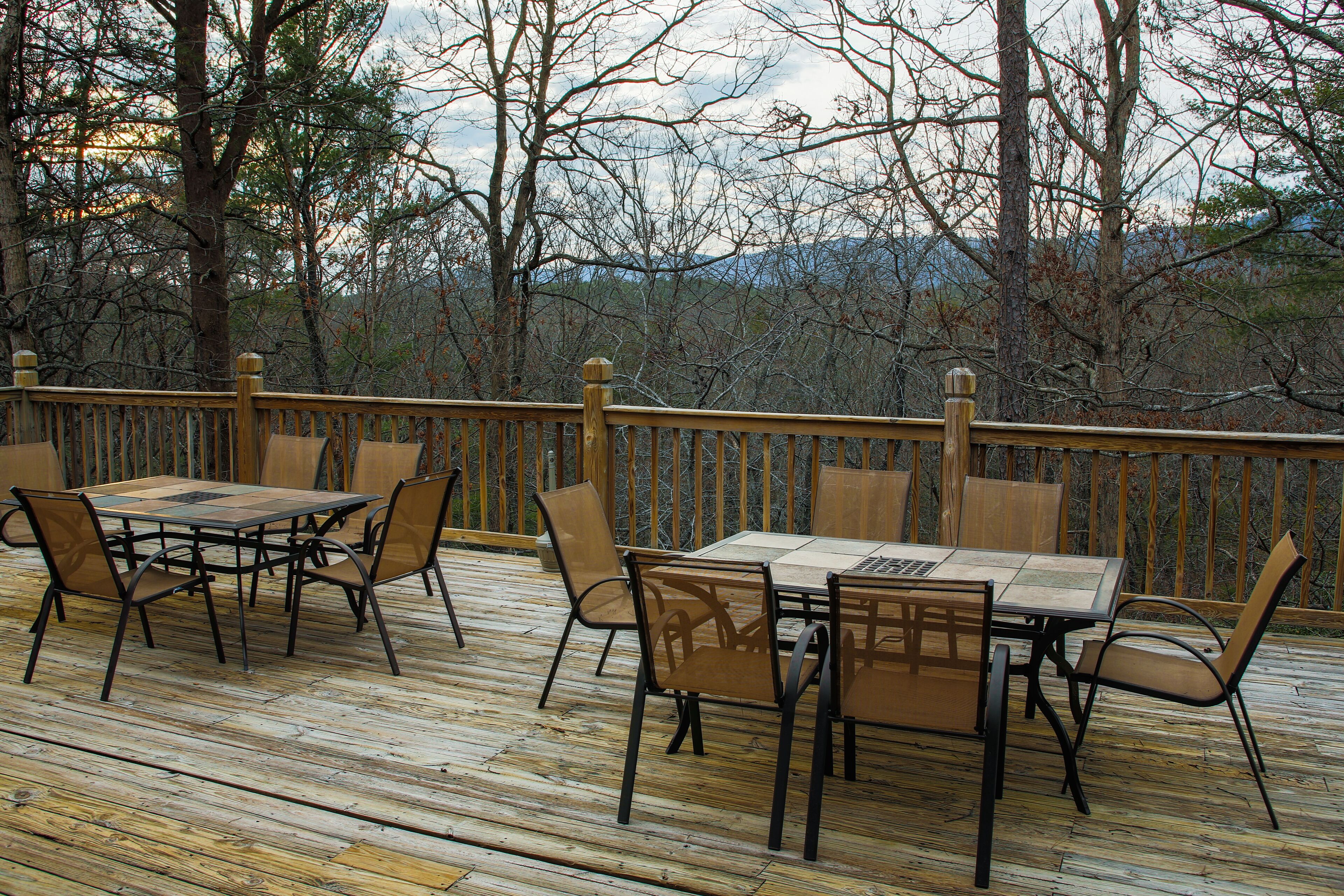 A wooden deck with a table and chairs, surrounded by trees.