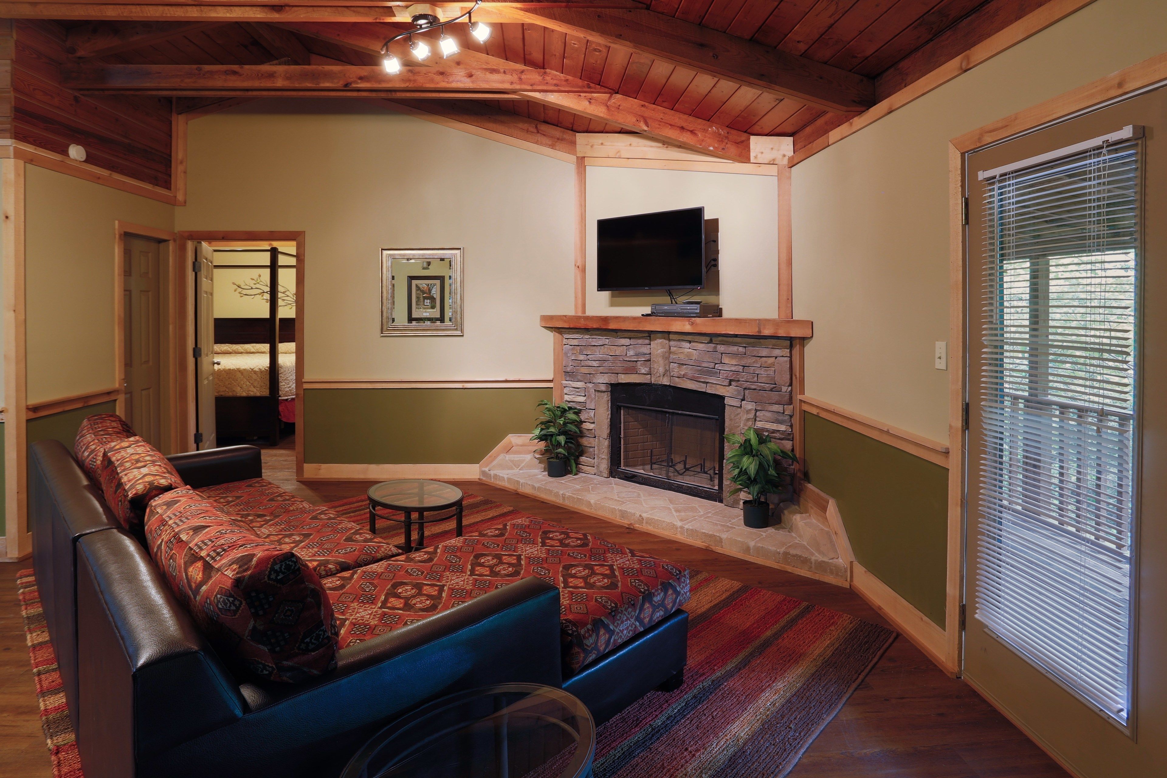 Una sala de estar acogedora con chimenea de piedra, un sofá modular grande y un televisor de pantalla plana sobre la chimenea.