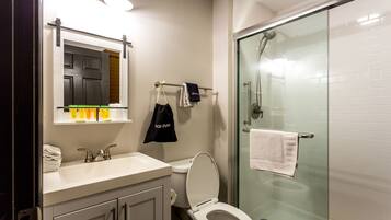 Un bagno moderno con box doccia in vetro, lavandino bianco e servizi igienici.