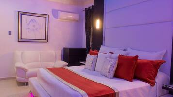 Un dormitorio moderno con una cama grande, un sofá blanco y un televisor de pantalla plana.
