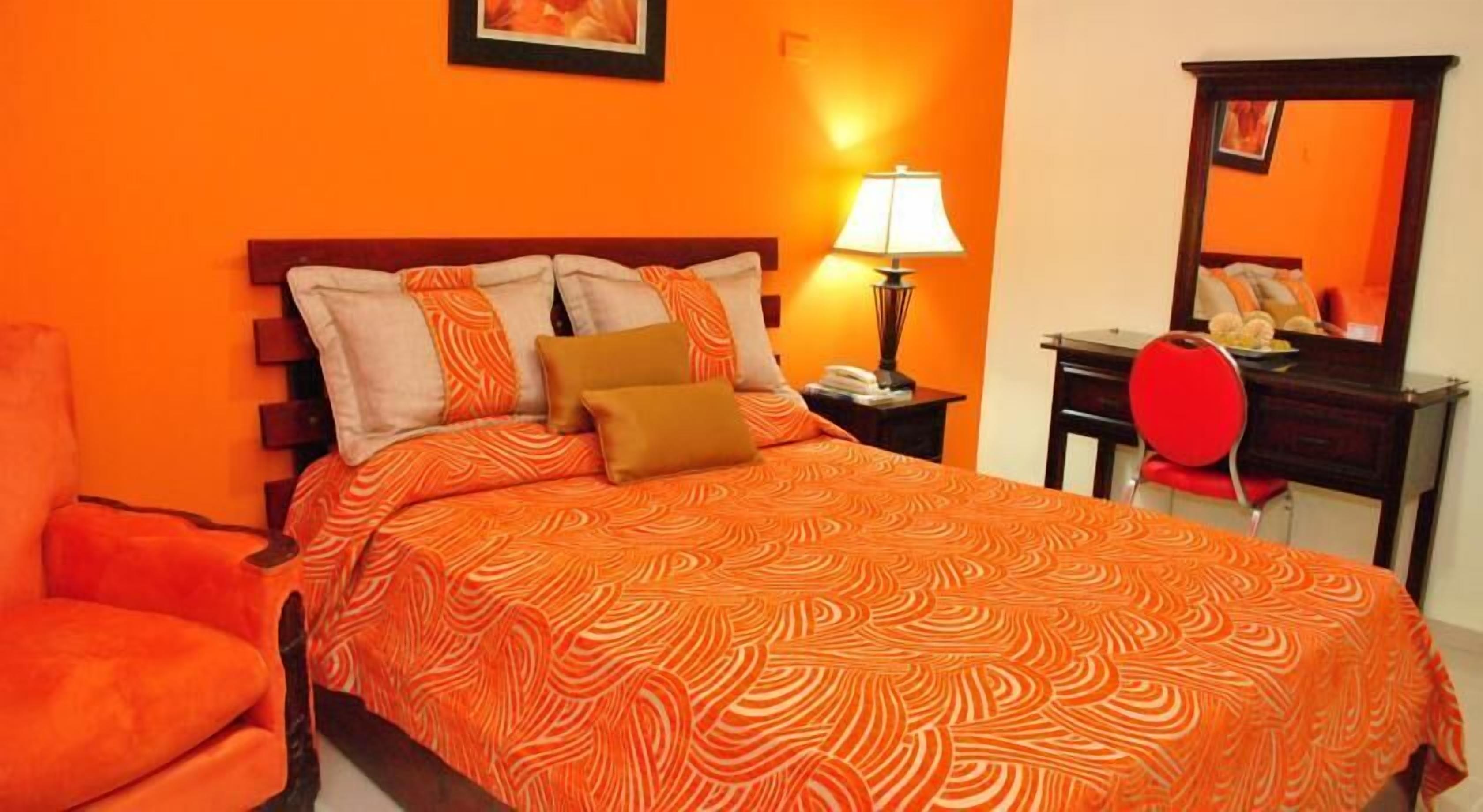 Um quarto com uma cama, uma cadeira, um abajur e um espelho.