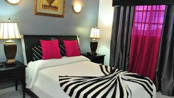 Una camera d'albergo con un letto, due comodini, due lampade, un quadro appeso alla parete e una finestra con tende.
