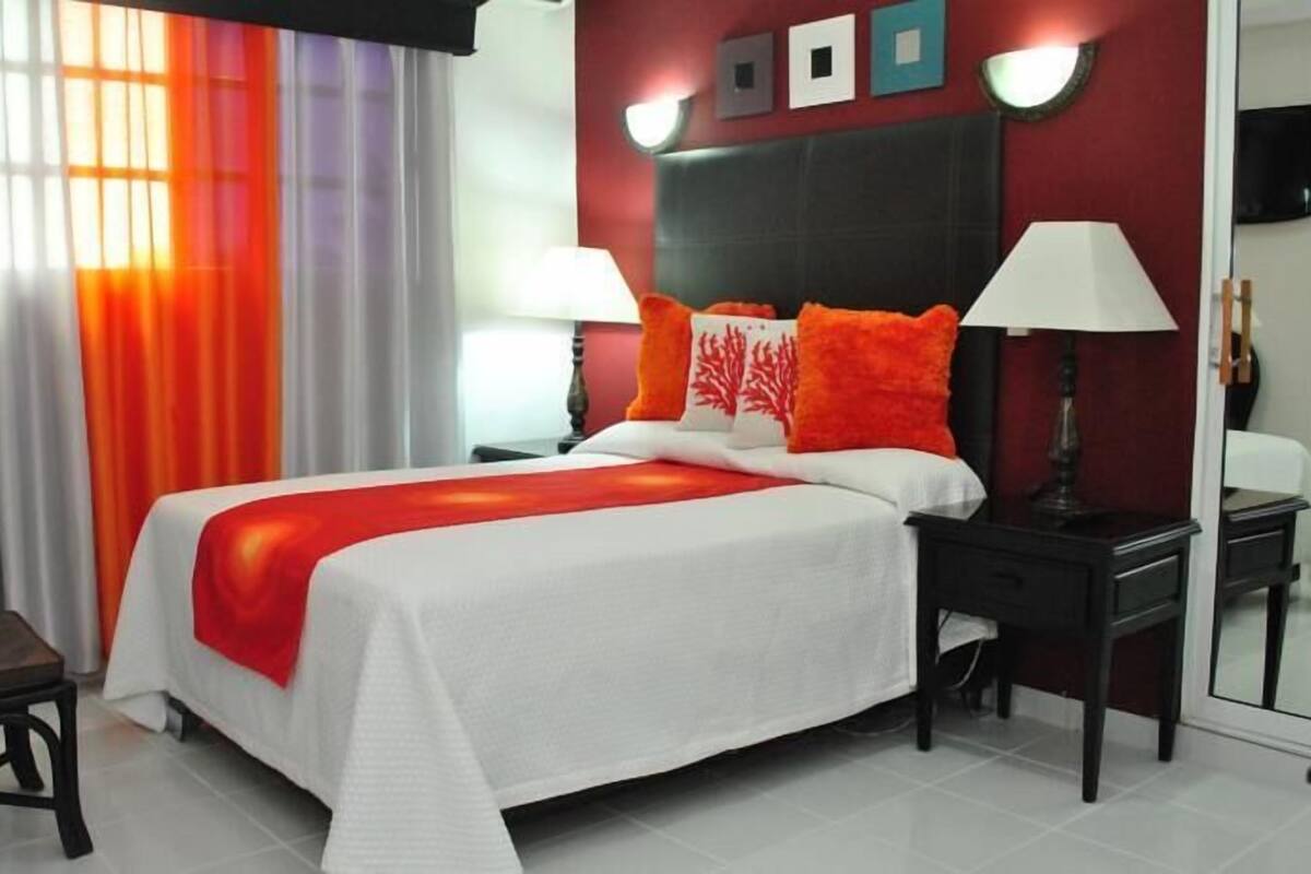 Une chambre d’hôtel avec un grand lit, une table de chevet, une chaise et un miroir.