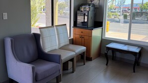 A room with a ceiling fan, a bench, a small table, and a window with a view of a parking lot. - National Inn Garden Grove (Garden Grove)