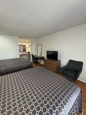 A hotel room with two beds, a desk, a chair, a TV, and a mirror. - National Inn Garden Grove (Garden Grove)