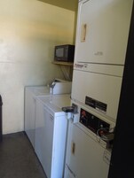 Un cuarto de lavado con lavadora, secadora y un microondas en un estante.