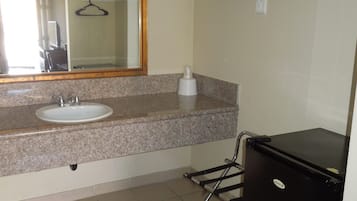 Une salle de bain équipée d’un lavabo, d’un miroir, d’un porte-serviettes et d’un réfrigérateur noir.