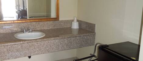 A bathroom with a sink, mirror, towel rack, and a black refrigerator.